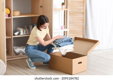 Young woman arranging clothes at wardrobe