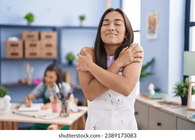 Young woman at art studio hugging oneself happy and positive, smiling confident. self love and self care  - Powered by Shutterstock