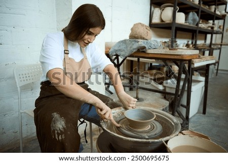 Similar – Young female sitting by table and making clay or ceramic mug