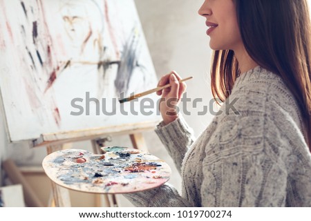 Young woman artist painting at home creative holding palette close-up