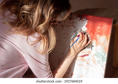 A young woman artist paints a picture by numbers. Sunny day. Creativity and art relieve stress. Hobby at home. Calming, relaxing, meditation. Self-isolation. Lock down. Introvert