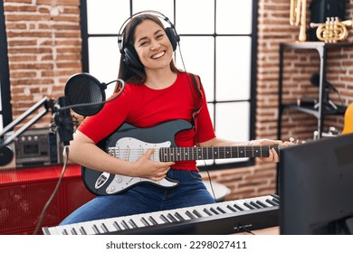 Young woman artist playing electrical guitar at music studio