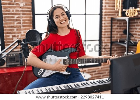 Young woman artist playing electrical guitar at music studio