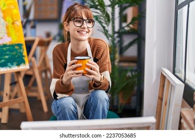 Young woman artist smiling confident drinking coffee at art studio - Powered by Shutterstock