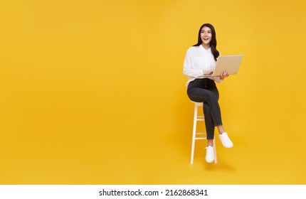 Young Woman Asian Happy Smiling. While Her Using Laptop Sitting On White Chair And Looking Isolate On Copy Space Yellow Background.