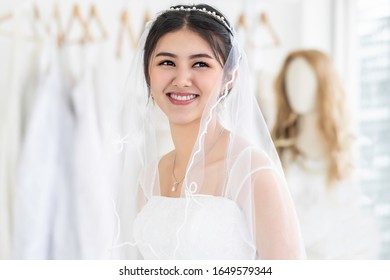 Young Woman Asian Smiling And Trying On Wedding Dress In A Shop.