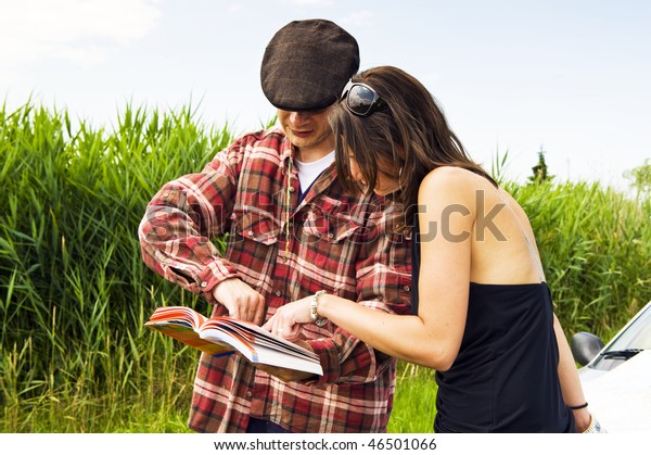 Young woman asking a farmer for advice on where to\
go, consulting a guide\
book