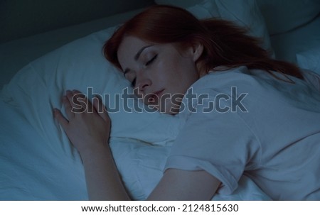 young woman asleep in bed at night - sleeping on stomach with her head on pillow