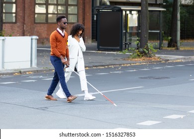 Young Woman Assisting Blind Man On Street