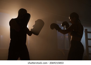 Young Woman Athlete in Boxing Gloves and Sport Clothes is Boxing With her Skillful Trainer. They Dodging Punches While Practicing on Boxing Ring - Powered by Shutterstock