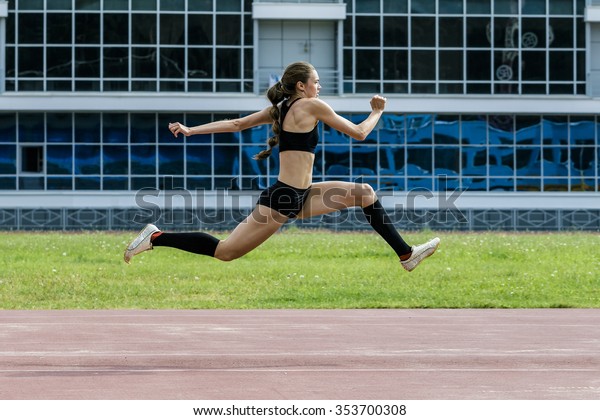 young woman athlete jumping triple jump\
in summer stadium. beautiful and sexy girl\
athlete