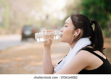 Young Woman Athlete Takes A Break, Drinking Water, Out On A Run On A Hot Day.