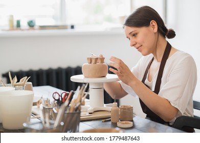 Young woman attaching clay product part to future ceramic product. Pottery workshop. - Powered by Shutterstock