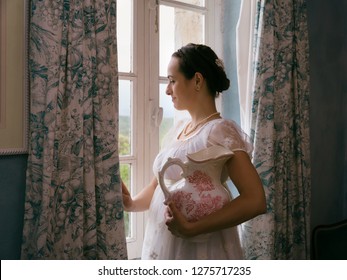 Young Woman In Authentic Regency Dress Near A Window Of A Classical Interior