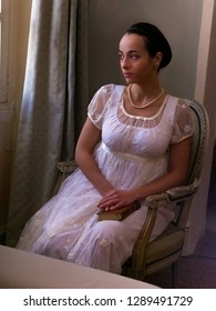 Young Woman In Authentic Regency Dress Near A Window Of A Classical Interior