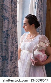 Young Woman In Authentic Regency Dress Near A Window Of A Classical Interior