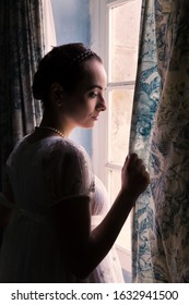 Young Woman In Authentic Regency Dress Near A Window Of A Classical Interior