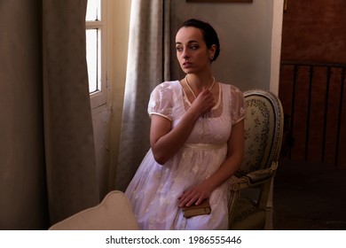 Young Woman In Authentic Regency Dress Near A Window Of A Classical Interior