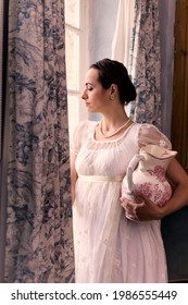 Young Woman In Authentic Regency Dress Near A Window Of A Classical Interior