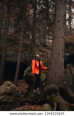 Young woman in the autumn forest. Misty landscape with mossy rocks. Cute smiley woman in the nature. Autumn forest hiking