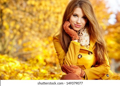 Young woman with autumn leaves in hand and fall yellow maple garden background  - Powered by Shutterstock