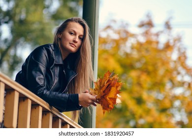 Young Woman With Autumn Leaves In Hand And Fall Yellow Maple Garden Background