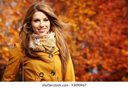 Young Woman With Autumn Leaves In Hand And Fall Yellow Maple Garden Background