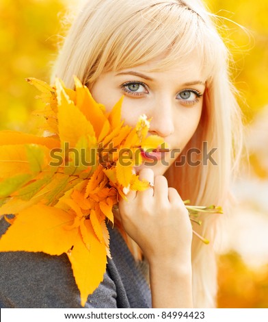 Young woman with autumn leaves in hand and fall yellow maple garden background