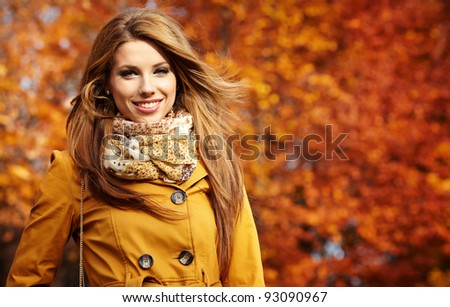 Young woman with autumn leaves in hand and fall yellow maple garden background