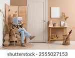 Young woman in autumn outfit sitting on chair and reading magazine at hallway