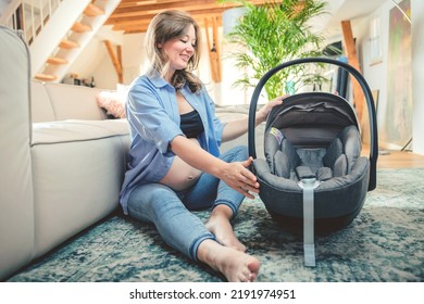 Young Woman With A Baby Car Seat Sitting On The Floor At Home