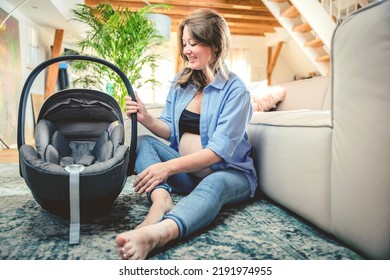 Young Woman With A Baby Car Seat Sitting On The Floor At Home