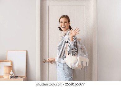 Young woman with backpack opening door in hallway - Powered by Shutterstock