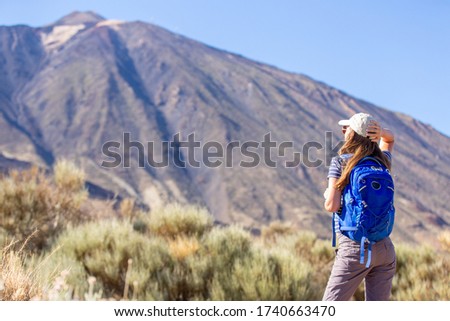 Young woman with backpack standing near Teide volcano on Tenerife. Nature tourism concept background with copy space