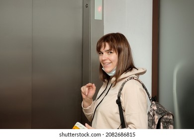 A Young Woman With A Backpack Stands By The Elevator And Smiles.