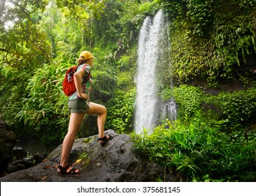 young woman backpacker looking at the waterfall in jungles.Ecotourism concept image travel girl