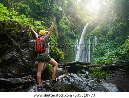 young woman backpacker looking at the waterfall in wild jungles.
Ecotourism, travel concept and discovery of beautiful places. Indonesia.