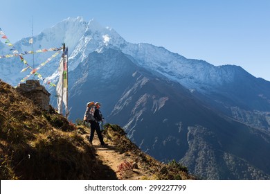 Young woman backpacker standing buddhist stupa in front Kangtega mountain snow peaks ridge. Everest Base Camp route trail, Nepal trekking, Himalaya tourism.