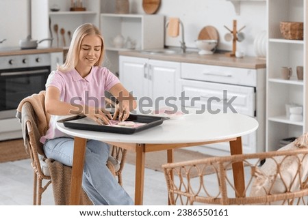 Young woman bagging cookies in kitchen. Breast cancer awareness concept