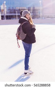 Young Woman With Bagpack Skates At Outdoor Skate Rink In Winter