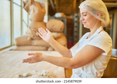 Young Woman Baker Slapping Flour From Hands While Kneading Dough For Baking In Bakery