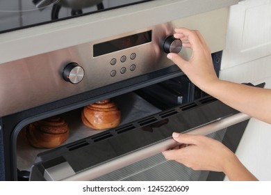 Young Woman Baking Buns In Electric Oven, Closeup