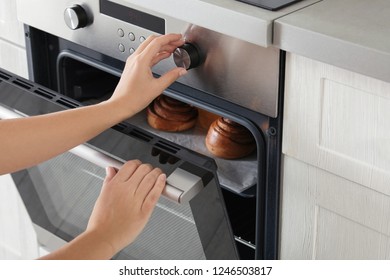 Young Woman Baking Buns In Electric Oven, Closeup