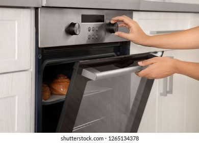 Young Woman Baking Buns In Electric Oven, Closeup