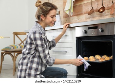 Young Woman Baking Cookies In Oven At Home