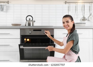 Young Woman Baking Something In Oven At Home