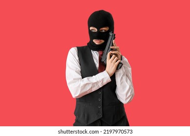 Young Woman In Balaclava With Gun Against Red Background