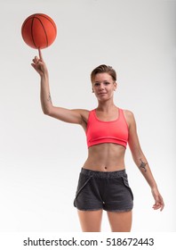 Young Woman Balancing A Basketball On Her Finger And Smiling To You