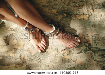 young woman bare feet on tree surface with boho style jewelry anklets and toe rings summer day oitdoor