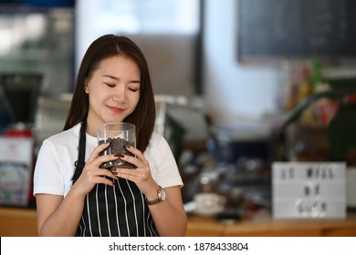 Young woman barista smelling and checking quality of coffee beans at coffee shop. - Powered by Shutterstock